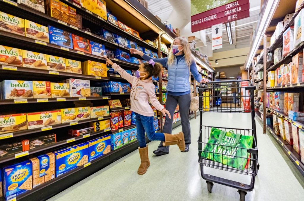 A woman and a child shopping with reusable bags.